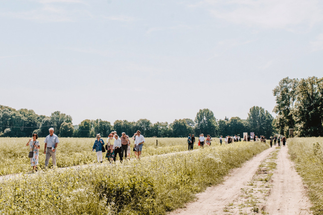 Besucher*innen auf einem Feldweg entlang des Lyrikwegs