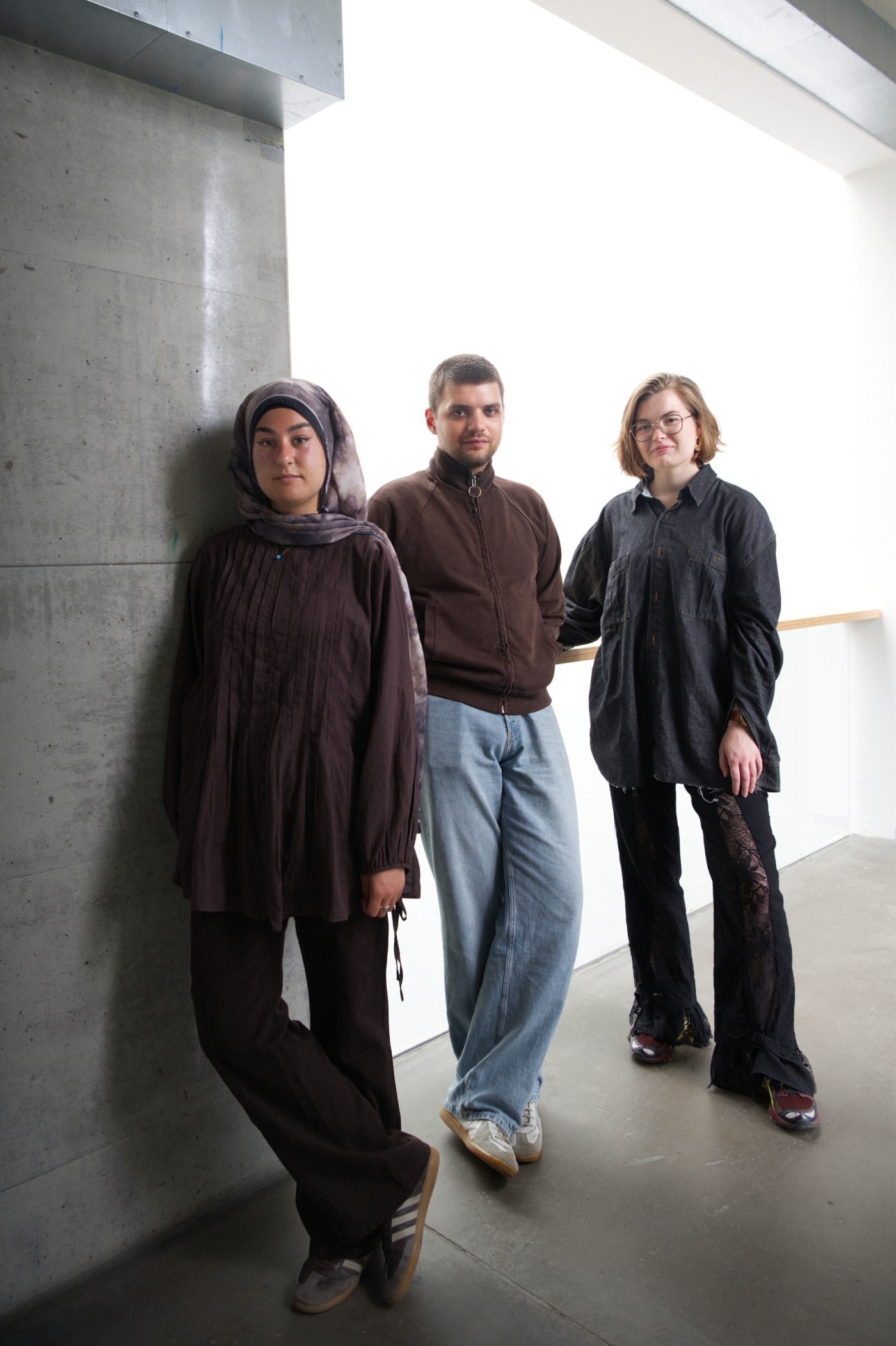 Tuğba Durukan, Mona Marie Eilers und Jakob Mönch stehen vor einer Betonwand und einem Geländer.