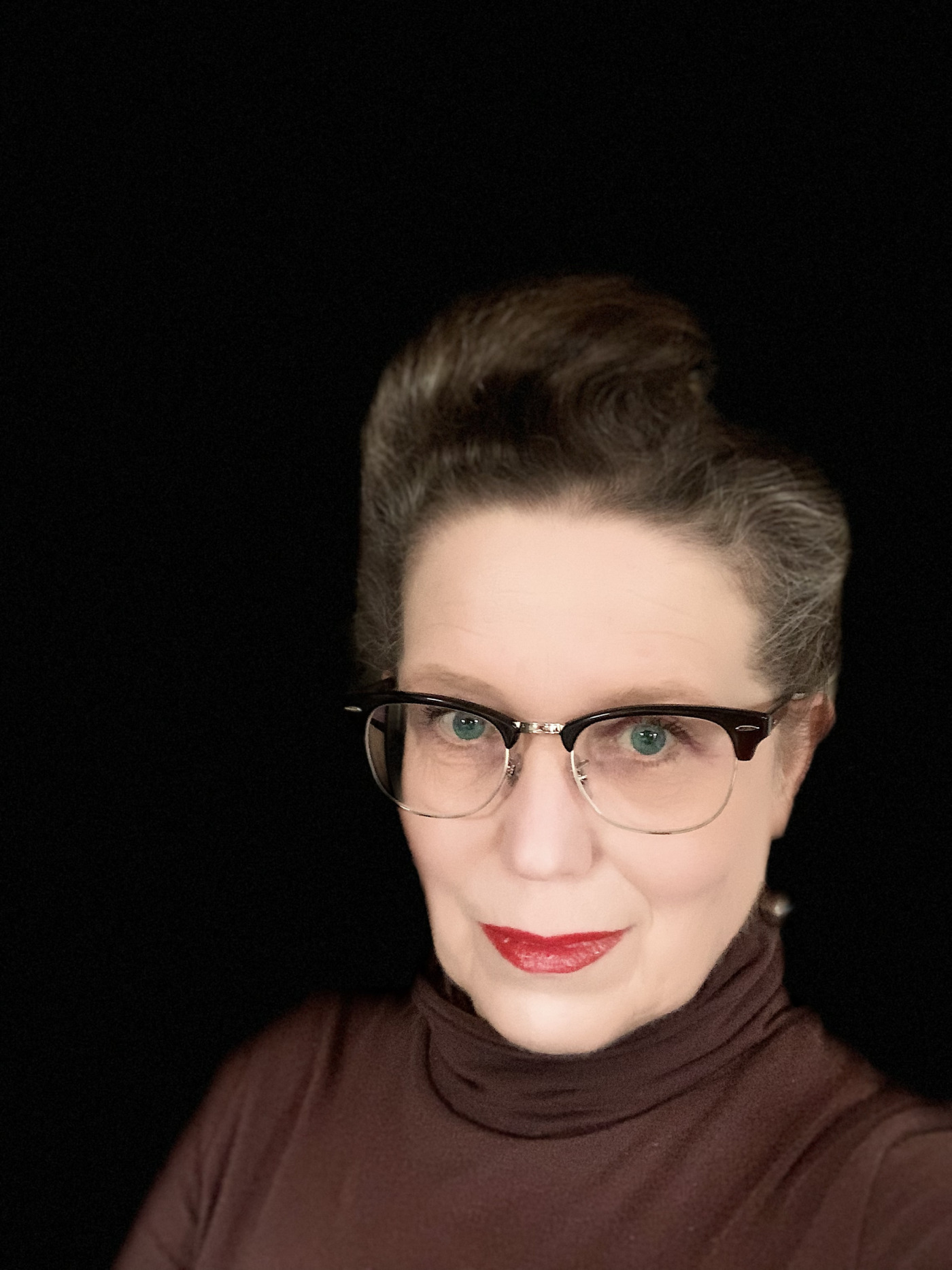 Portrait Foto von Brigitte Dunkel. Selfie vor einem schwarzen Hintergrund.