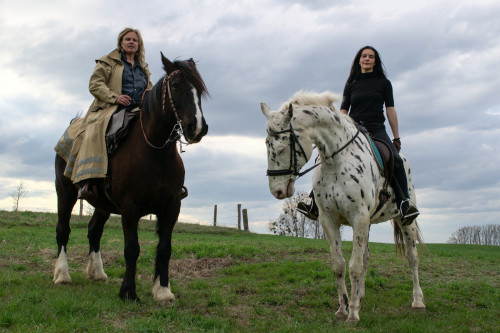 Karen Duve und Bettina Bruns sitzen auf Pferden auf einer grünen Wiesen Landschaft.