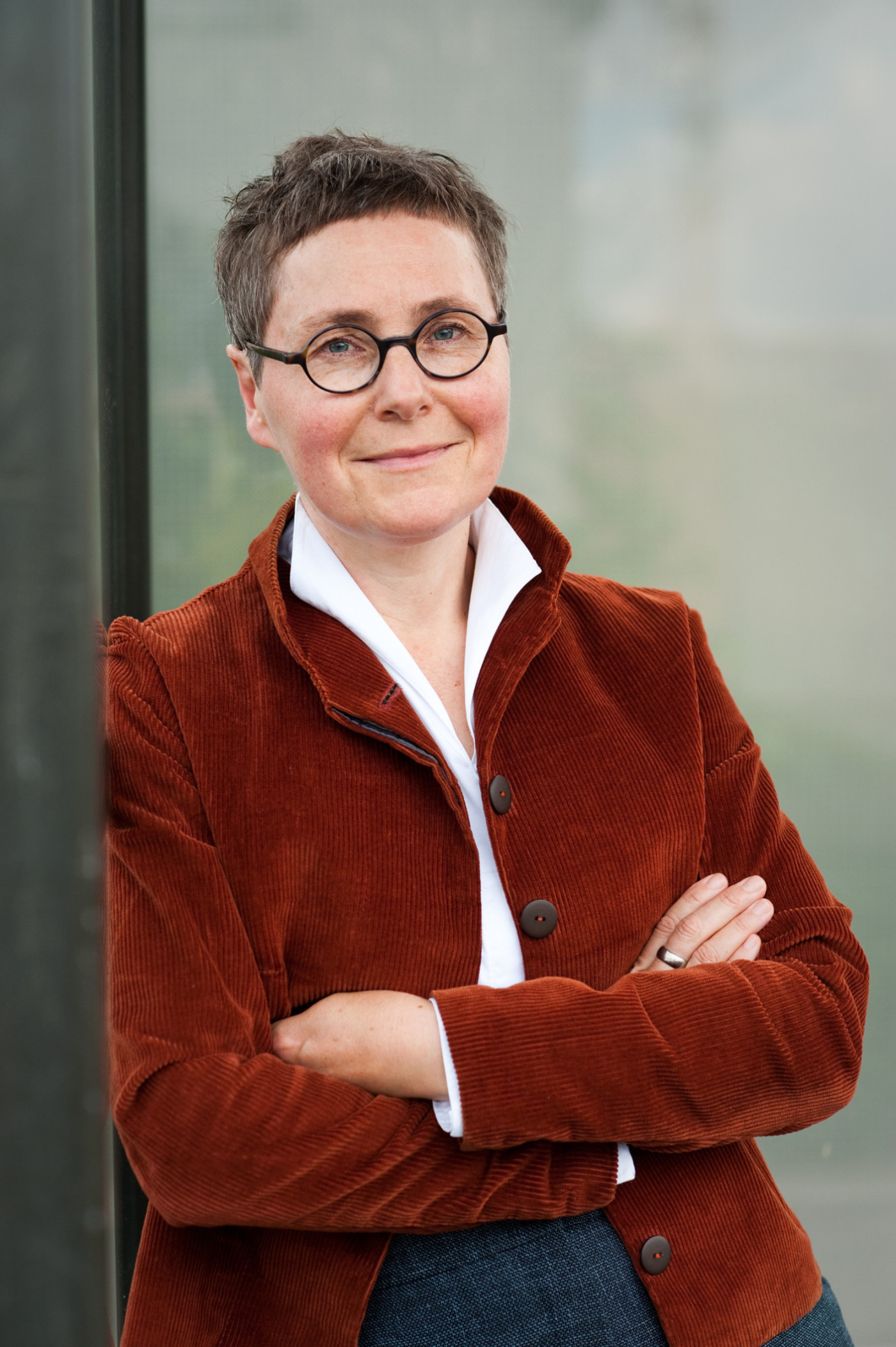 Angela Steidele steht mich verschr&auml;nkten Armen an eine Mauer gelehnt.