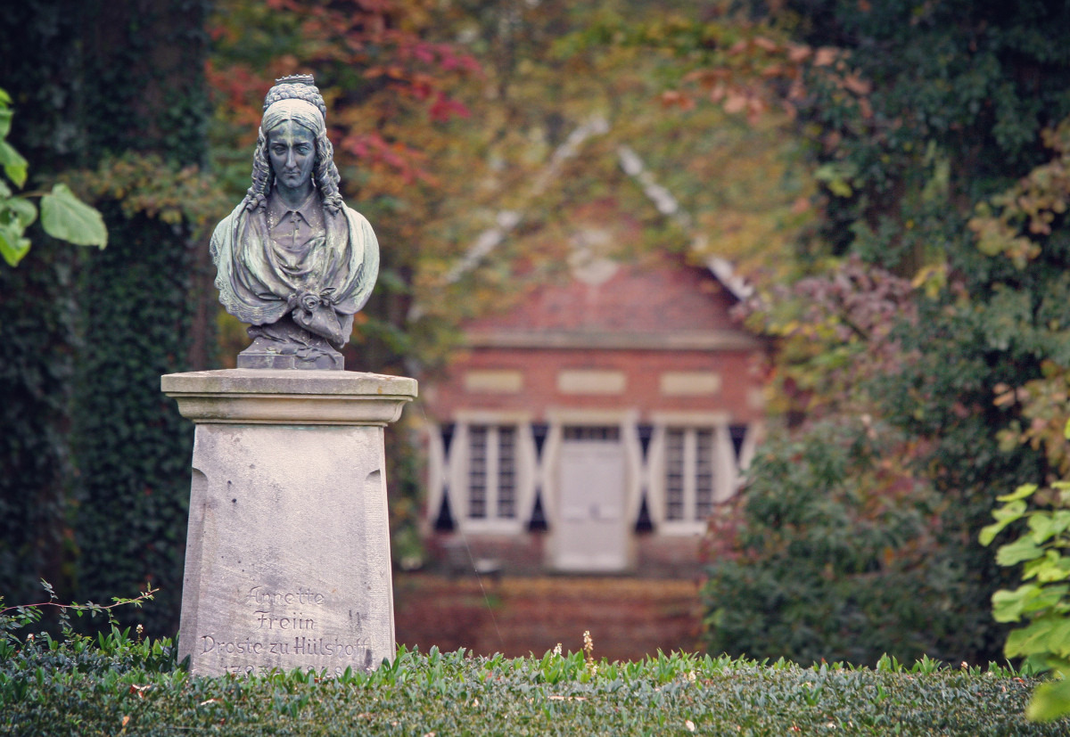 Büste, die das Abbild von Annette von Droste-Hülshoff zeigt. Die Büste steht auch einem Sockel im Park von Burg Hülshoff. Im Hintergrund liegt das »Teehäuschen«. Der Blick von Droste ist nach unten gerichtet. Ihre Haare sind, für die Zeit des Biedermeier typisch, am Hinterkopf hochgesteckt und an den Schläfen gelockt.