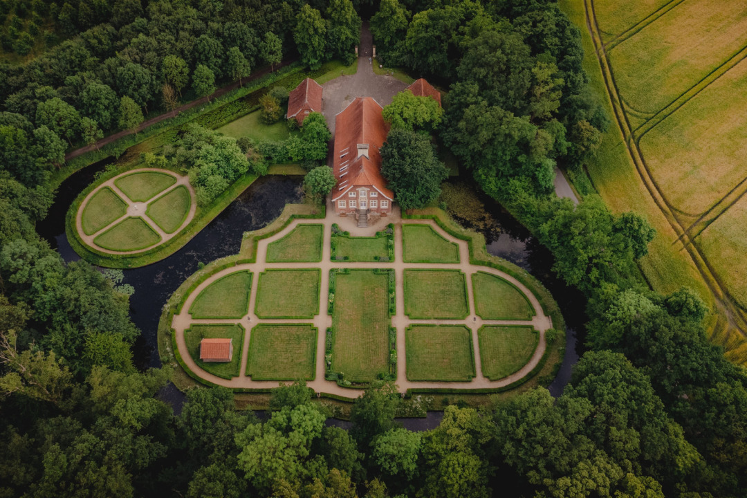 Haus R&uuml;schhaus samt Gartenanlage und Umgebung aus der Vogelperspektive. Das Grundst&uuml;ck ist von B&auml;umen und angrenzend Feldern umgeben.