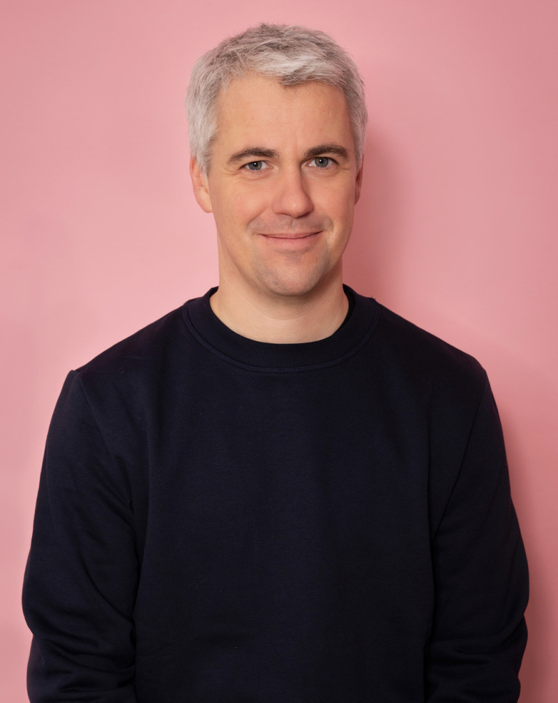 Portrait von Andreas B&uuml;lhoff vor einem rosa Hintergrund.